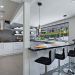 Teraslı geniş bir evin iç kısmında beyaz bir mutfak tasarımı