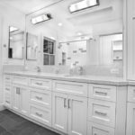 Balta vannas istaba ar pelēku flīžu grīdu un balta granīta darba virsmu