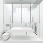 Salle de bain blanche avec un mur miroir