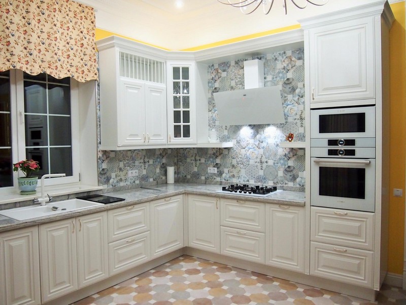 Stūra virtuves dizains ar baltām fasādēm.