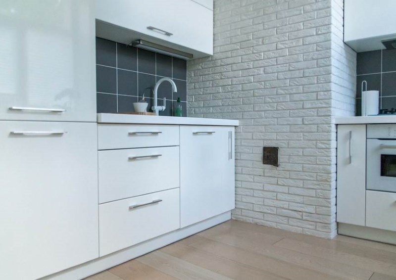 Minimalist white kitchen interior with brick wall