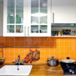 Oranžais flīžu priekšauts paneļu mājas virtuvē