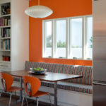 Mur orange derrière le canapé dans le salon-cuisine