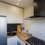 Blat de lucru din lemn și dulapuri luminoase în bucătăria unui apartament din oraș