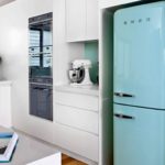 Turquoise refrigerator in the kitchen with white furniture