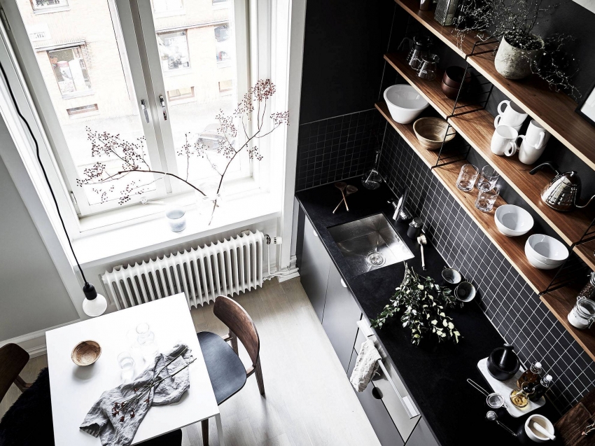 Kitchen interior in black and white with wooden shelves.