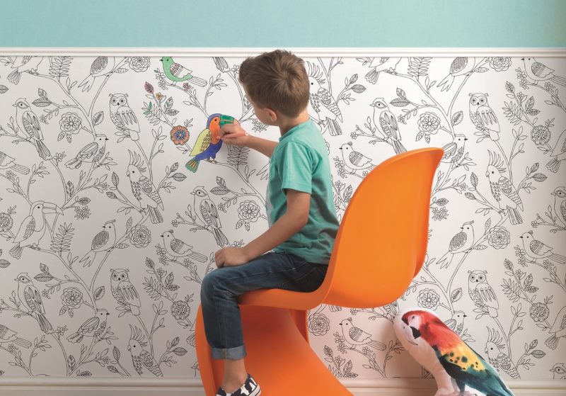 Garçon peint du papier peint en papier sur le mur d'une chambre d'enfant
