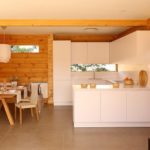 Bucătărie albă strictă în casă cu garnituri de lemn