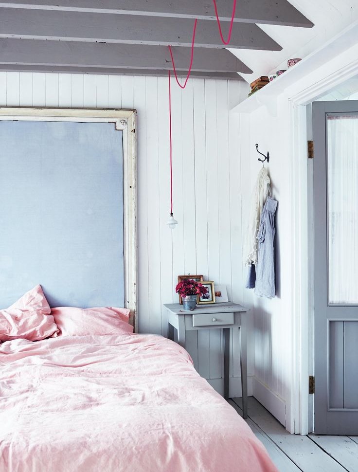 Mavi duvarlı bir yatak odasında pembe yatak örtüsü