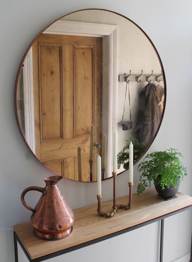 Un miroir rond dans un cadre fin en face d'une porte en bois