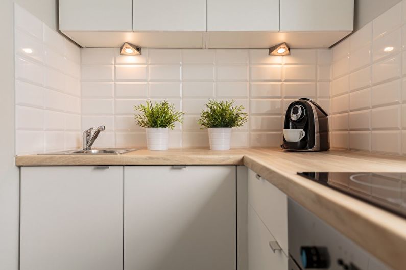 Pequeñas lámparas debajo de los armarios colgantes en una cocina compacta