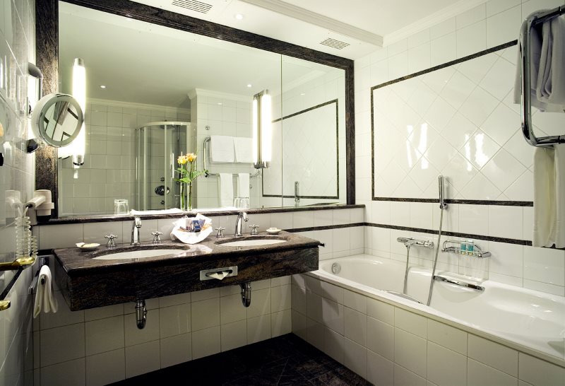 مرآة كبيرة على جدار حوض استحمام صغير