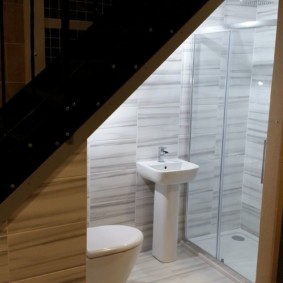 Cabine de douche sous l'escalier dans une maison en bois