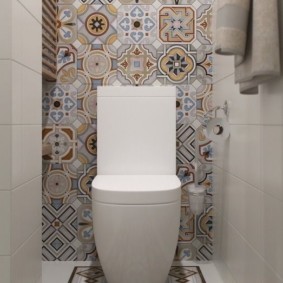 Patchwork style tile on toilet wall