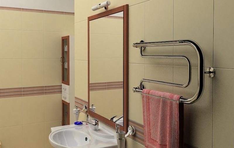 Porte-serviettes chauffé à l'eau sur le mur à côté du miroir