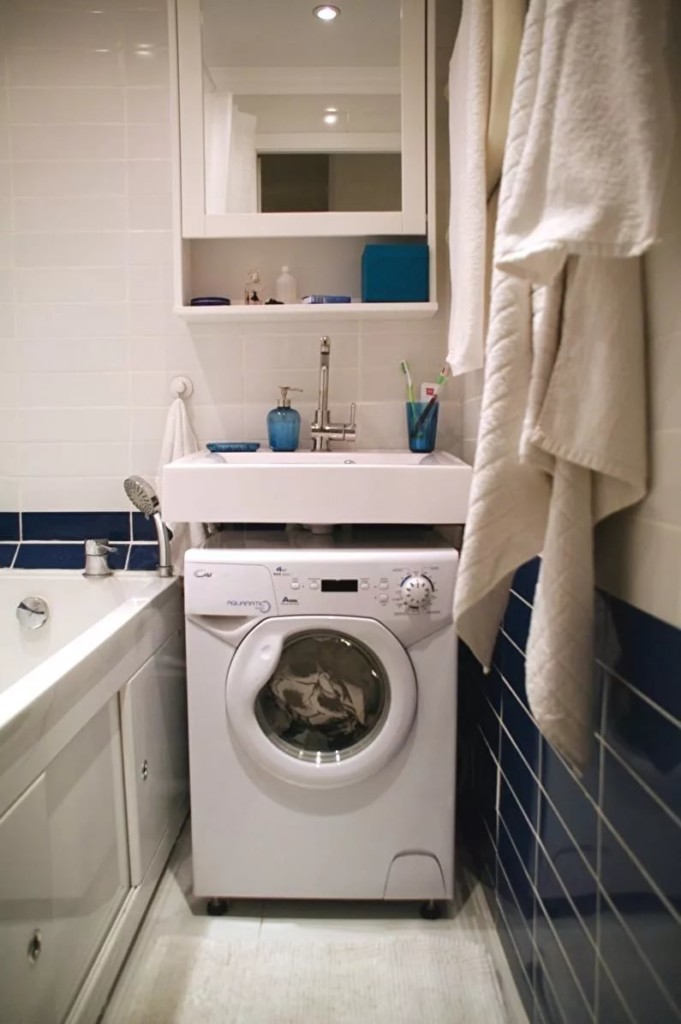 Porselen lavabonun altında beyaz çamaşır makinesi
