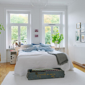חדר שינה לבן עם מיטה ליד החלון