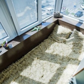 Kažokādu gultas pārklājs uz balkona grīdas