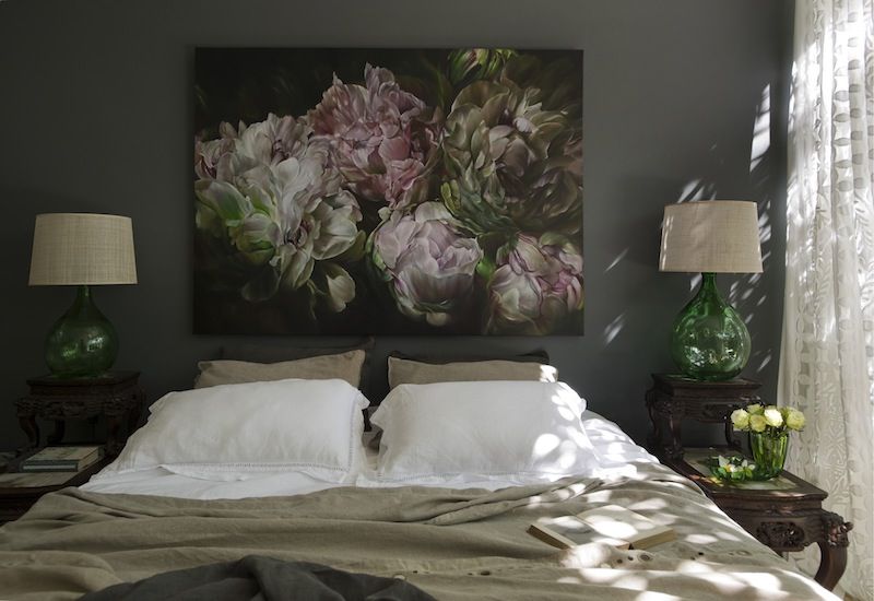 A picture with large flowers above the head of the bed