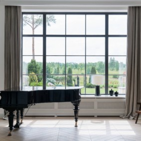 Büyük bir pencerenin önünde siyah bir piyano