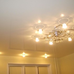 The combination of spotlights with a chandelier in the hall
