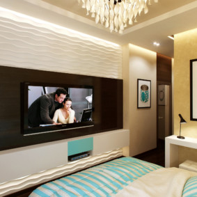 The interior of a small bedroom with a TV on the wall