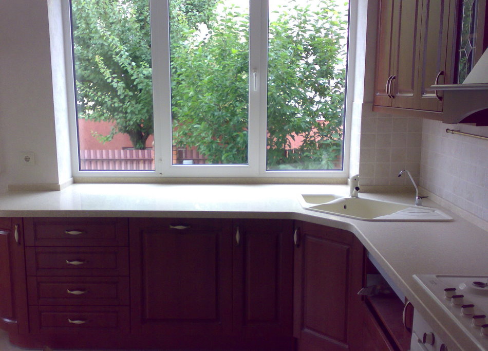 O chiuvetă trapezoidală în fața unei ferestre a bucătăriei într-o casă privată