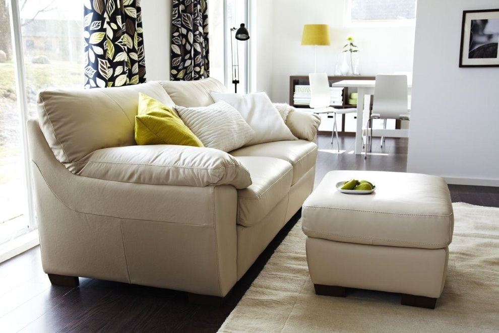 Pouf with leather upholstery in front of a sofa in the living room