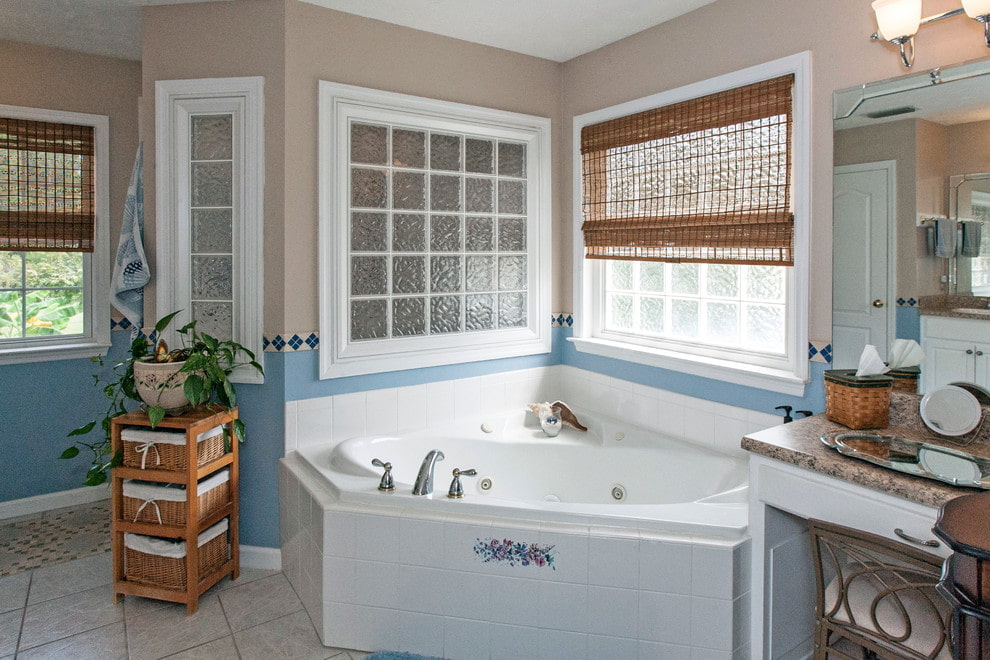 Cast iron corner bath in front of a window with a bamboo curtain