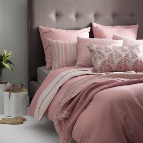 Oreillers roses sur un lit avec une tête de lit grise