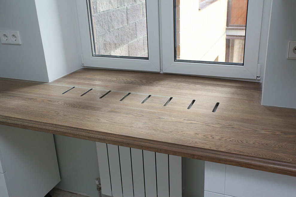 Wooden sill table with holes above the radiator
