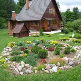 Small rock garden on a plot with a wooden house