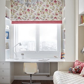 Çocuk odası penceresinin önünde bir masada beyaz dolapları