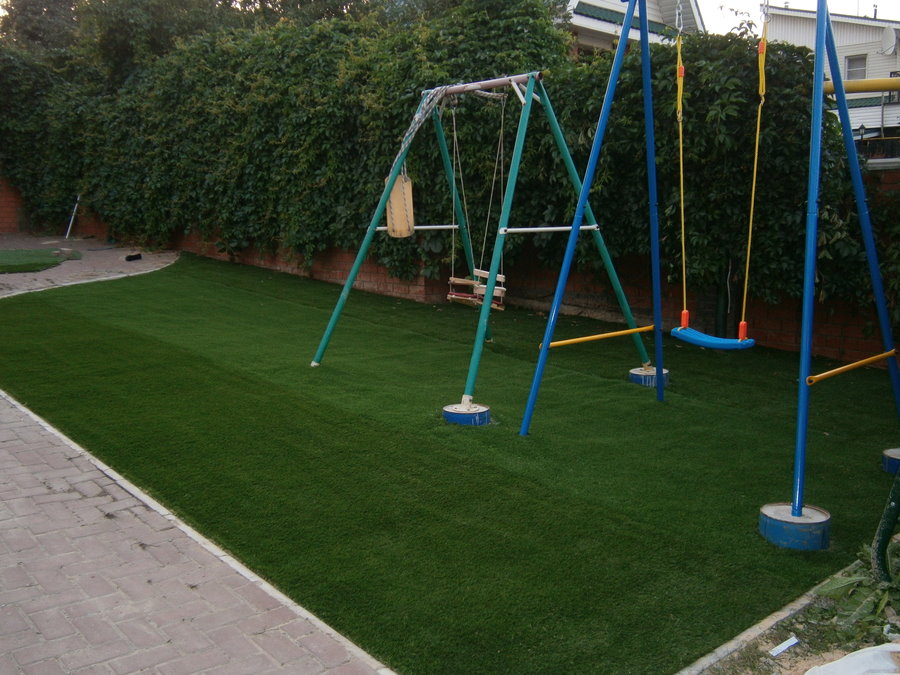 Balançoire pour enfants sur le terrain de jeu avec une pelouse de type sportif