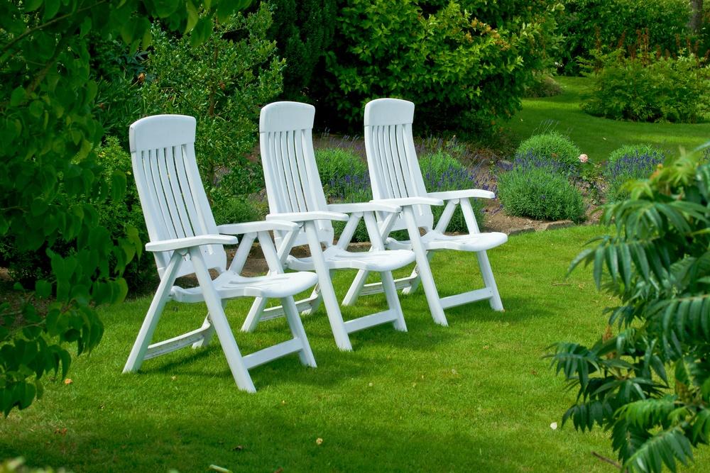 Bir park çim üzerinde beyaz Bahçe sandalyeleri