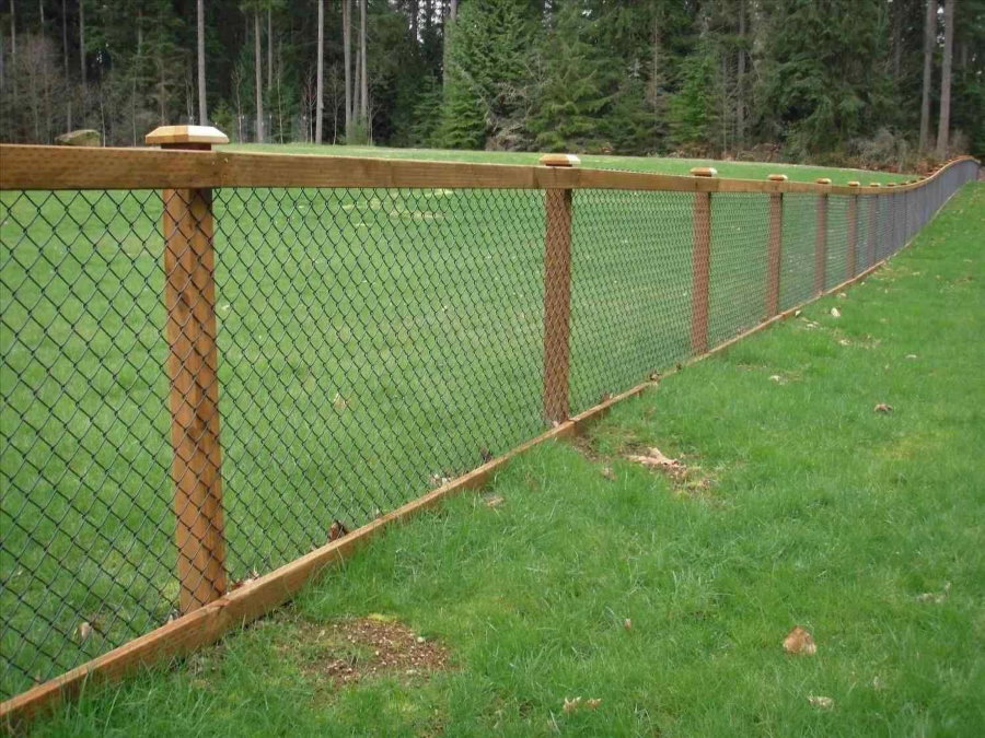 Bir bahçe sitesi ahşap direkleri üzerinde zincir bağlantı ızgarası ile çit