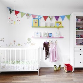 A garland of flags in a nursery with a white bed