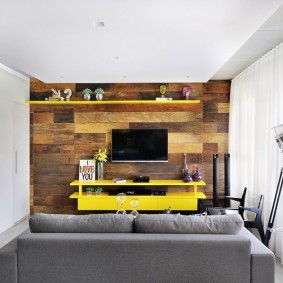 Dzeltenas mēbeles uz viesistabas koka sienas