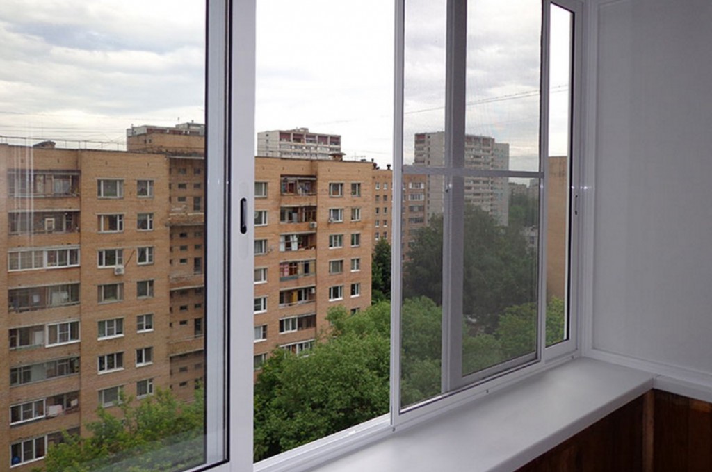 Çok katlı bir binanın bir dairesinde balkon camının açık kanadı