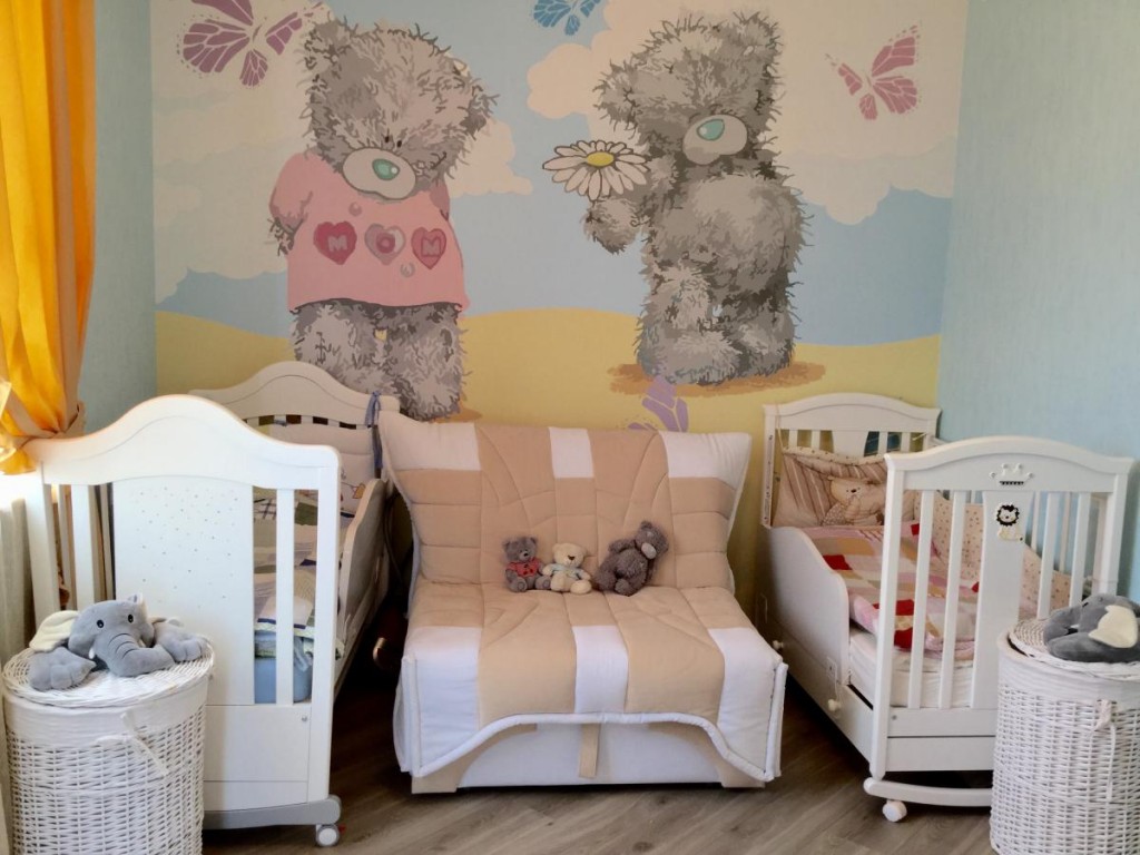 Cots in the room with bears on the wallpaper